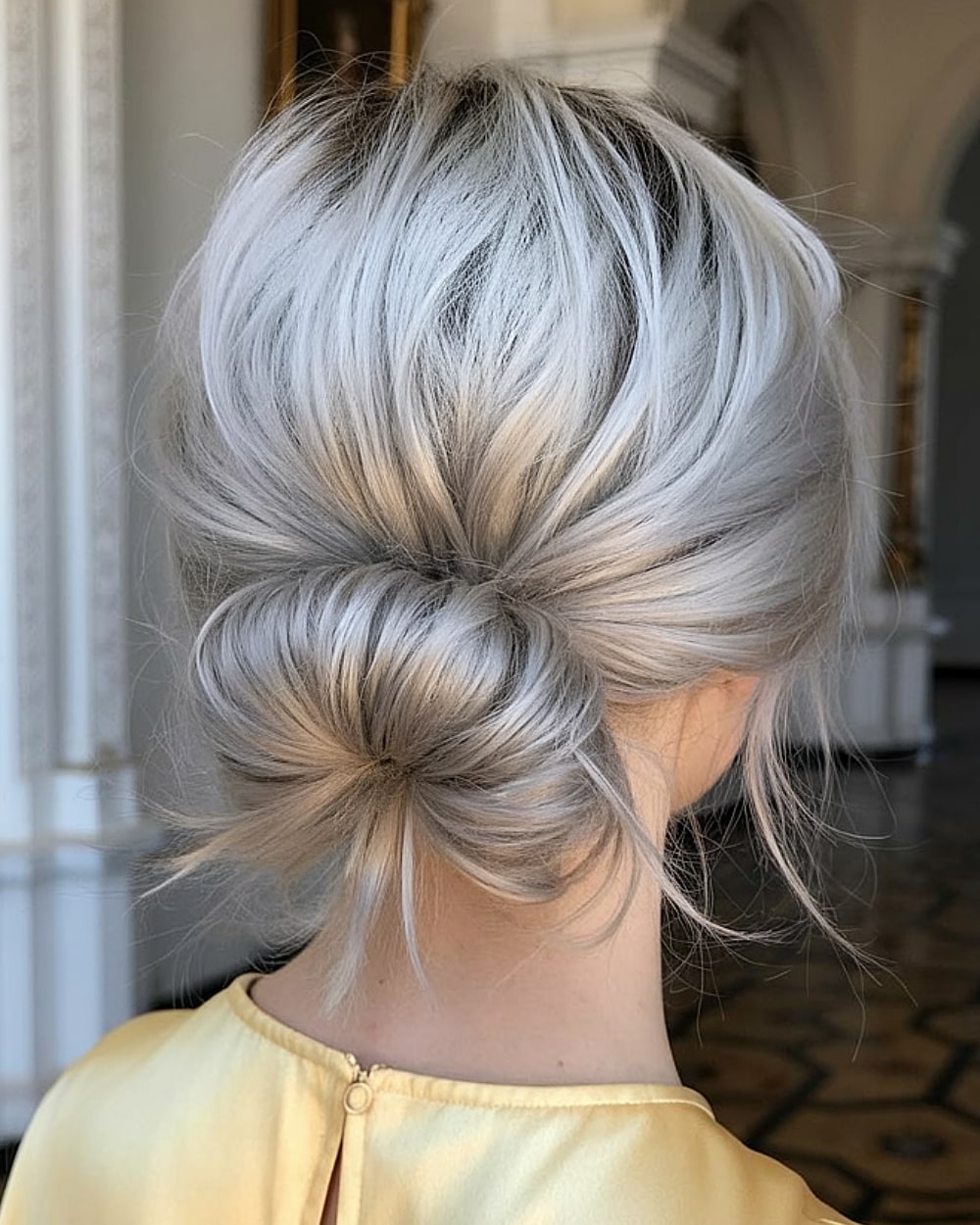 Textured silver-blonde low messy bun with soft volume, an effortless easy updo for fine hair types